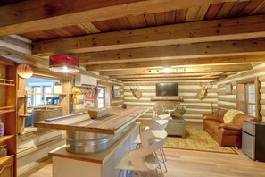 A log cabin interior with a central island, a sofa, and a television. - Across From Marina! Lake Seminole Fishing Lodge (Bainbridge)