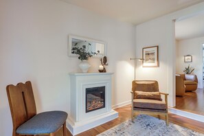 A living room with a fireplace, a chair, a rug, and a mirror. - Updated bungalow in The Dalles! Walk to Downtown! (The Dalles)