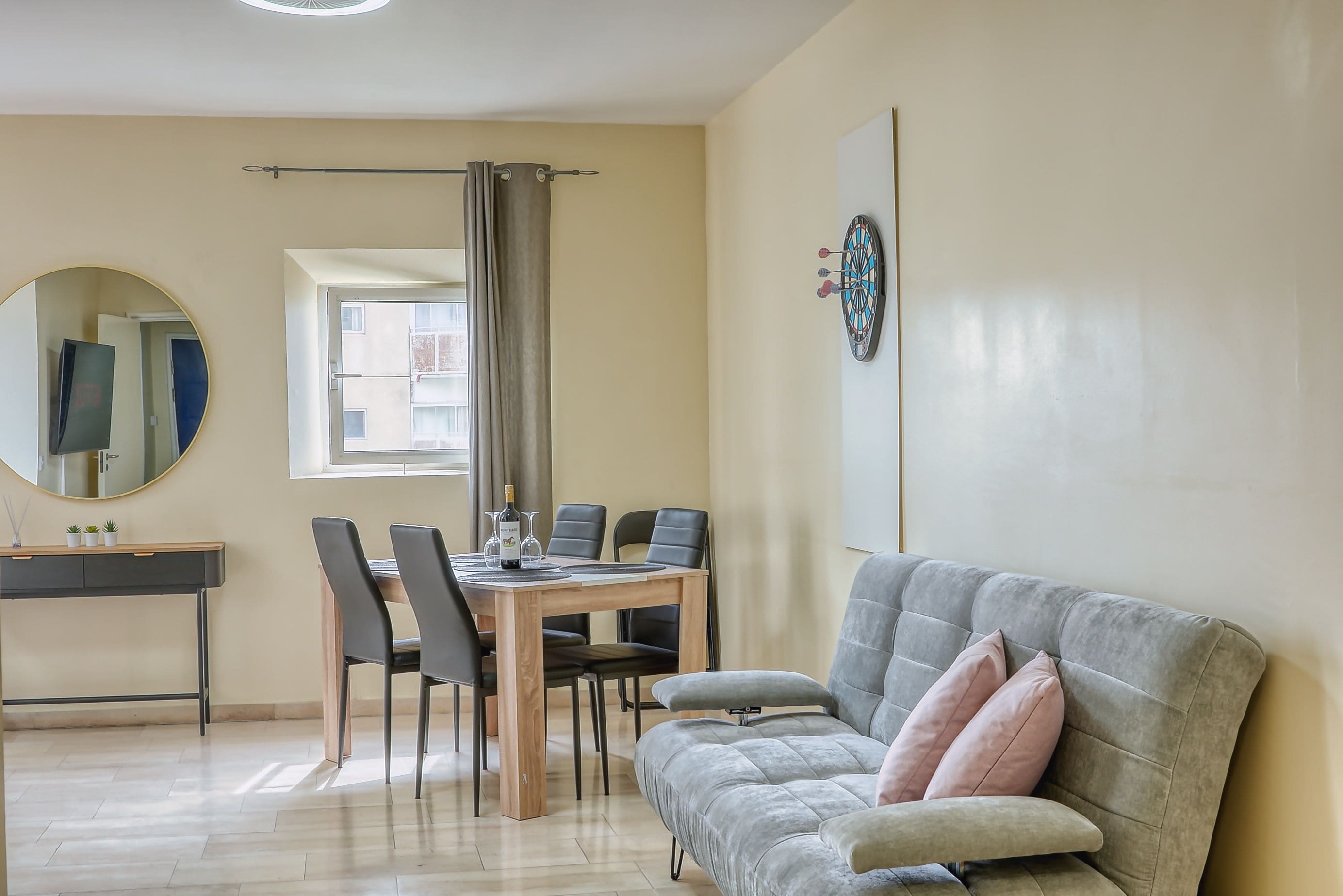 A dining area with a table, chairs, and a mirror.
