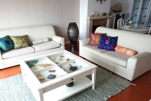 Ein Wohnzimmer mit zwei Sofas, einem Couchtisch mit Dekoration und einem Kamin.