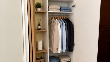 Ein begehbarer Kleiderschrank mit Kleiderstange, gefalteter Kleidung und Schuhen.