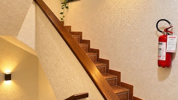 Eine Treppe mit Holzhufen und Handlauf, gesäumt von strukturierten Wänden und Wandleuchten.