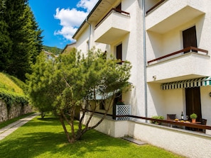 Ein zweigeschossiges Gebäude mit einem Balkon, einer Steinsäule und einem gepflegten Rasen.