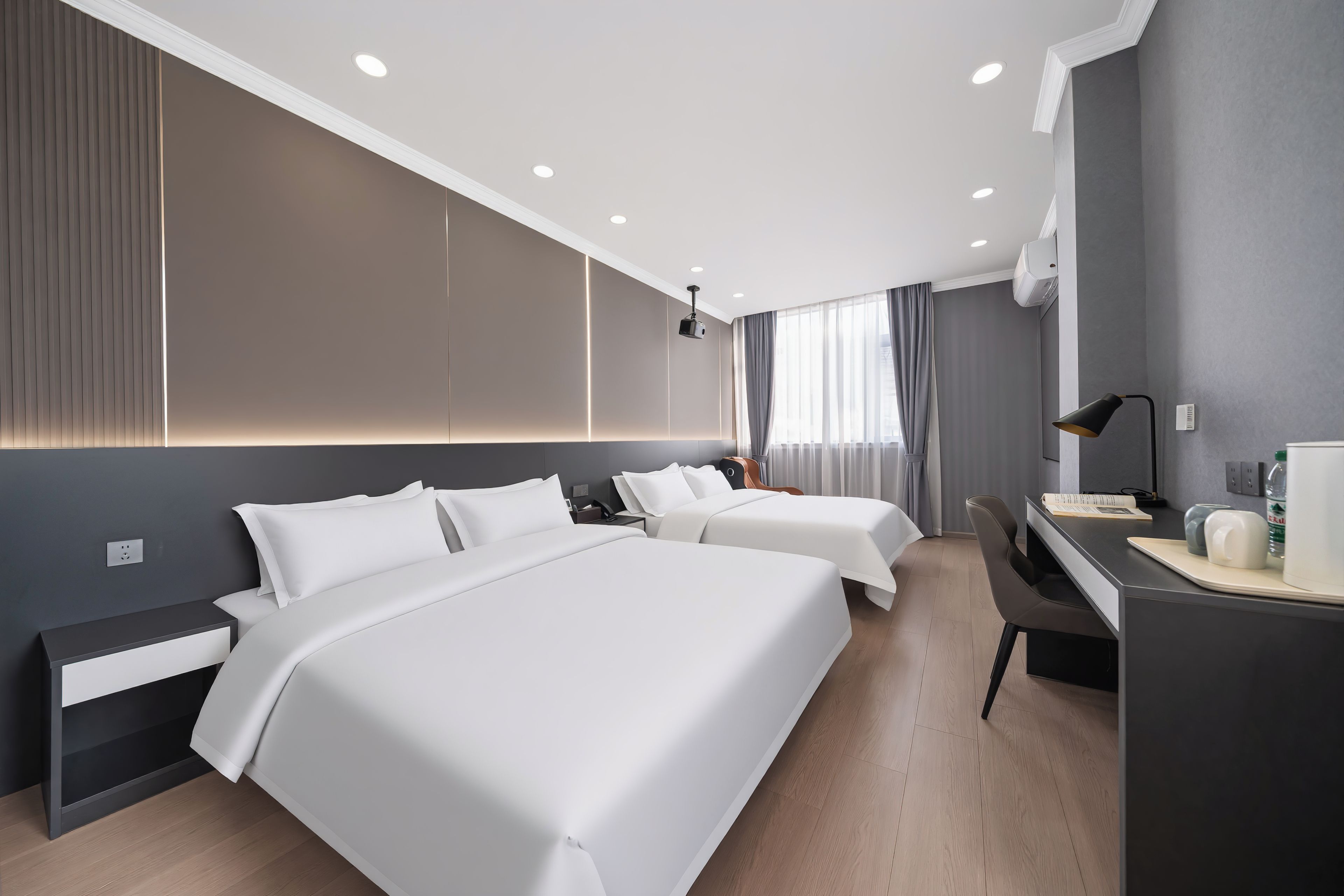 A hotel room with two beds, a desk, a chair, and a large window with curtains.