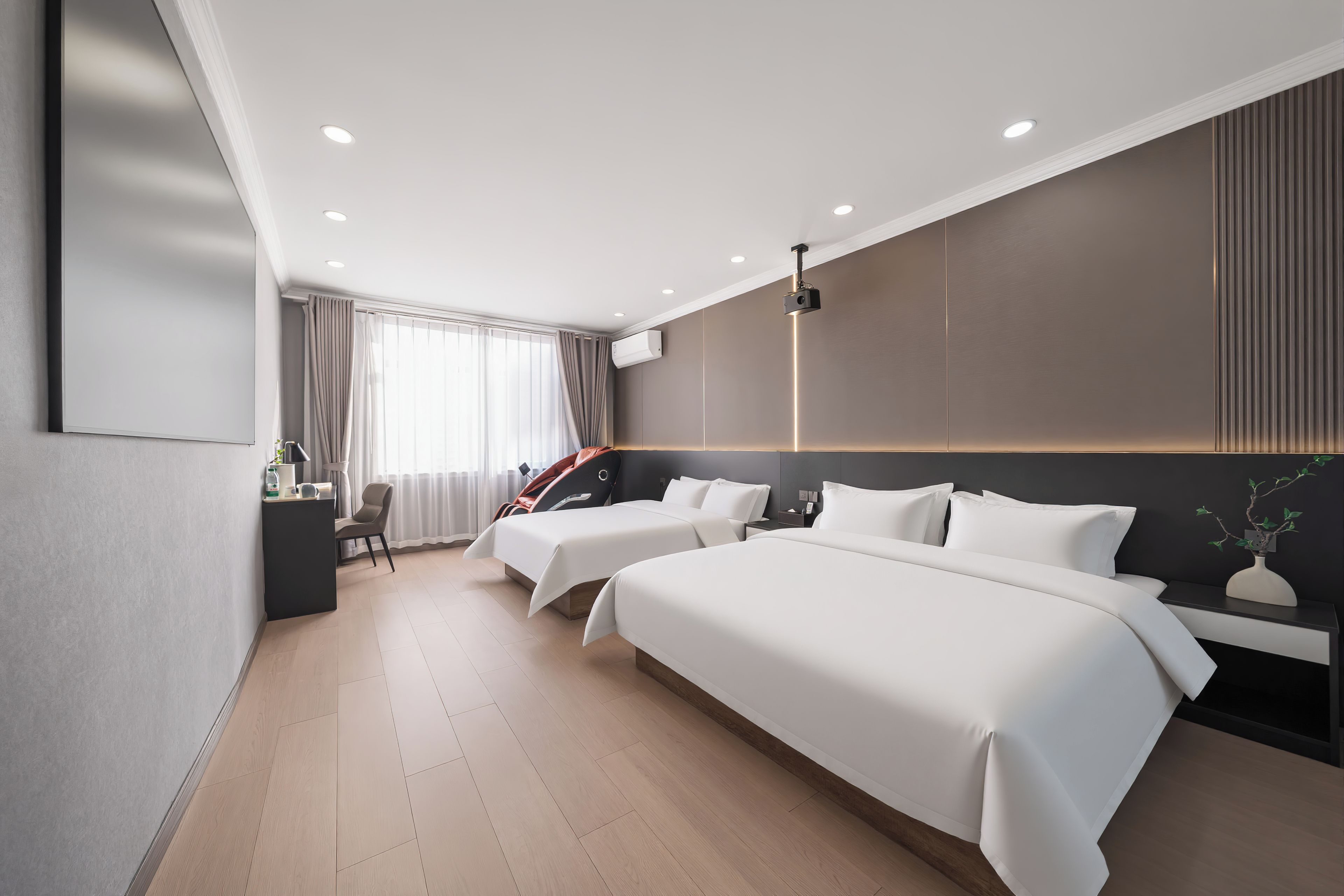 Una habitación de hotel moderna con dos camas, un escritorio, una silla y un ventanal con cortinas.
