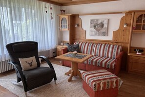 Un salon chaleureux avec un canapé, un fauteuil et une petite table sur laquelle est posé un vase.
