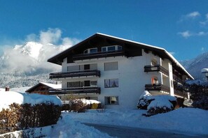 Un hôtel à plusieurs étages, doté de balcons, qui se dresse sur fond de montagnes enneigées.