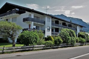 A two-story building with balconies, surrounded by greenery and mountains in the background. - Alpenflair holiday apartment 202 (Oberstdorf)