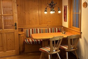 Un intérieur en bois avec un espace salon comprenant un banc, une table et un lustre.
