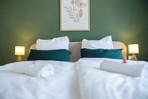A double bed with white and teal bedding, two bedside lamps, and a framed artwork on the wall. - Simply Stay Homes Bergliebe & Seeglück (Traunstein)