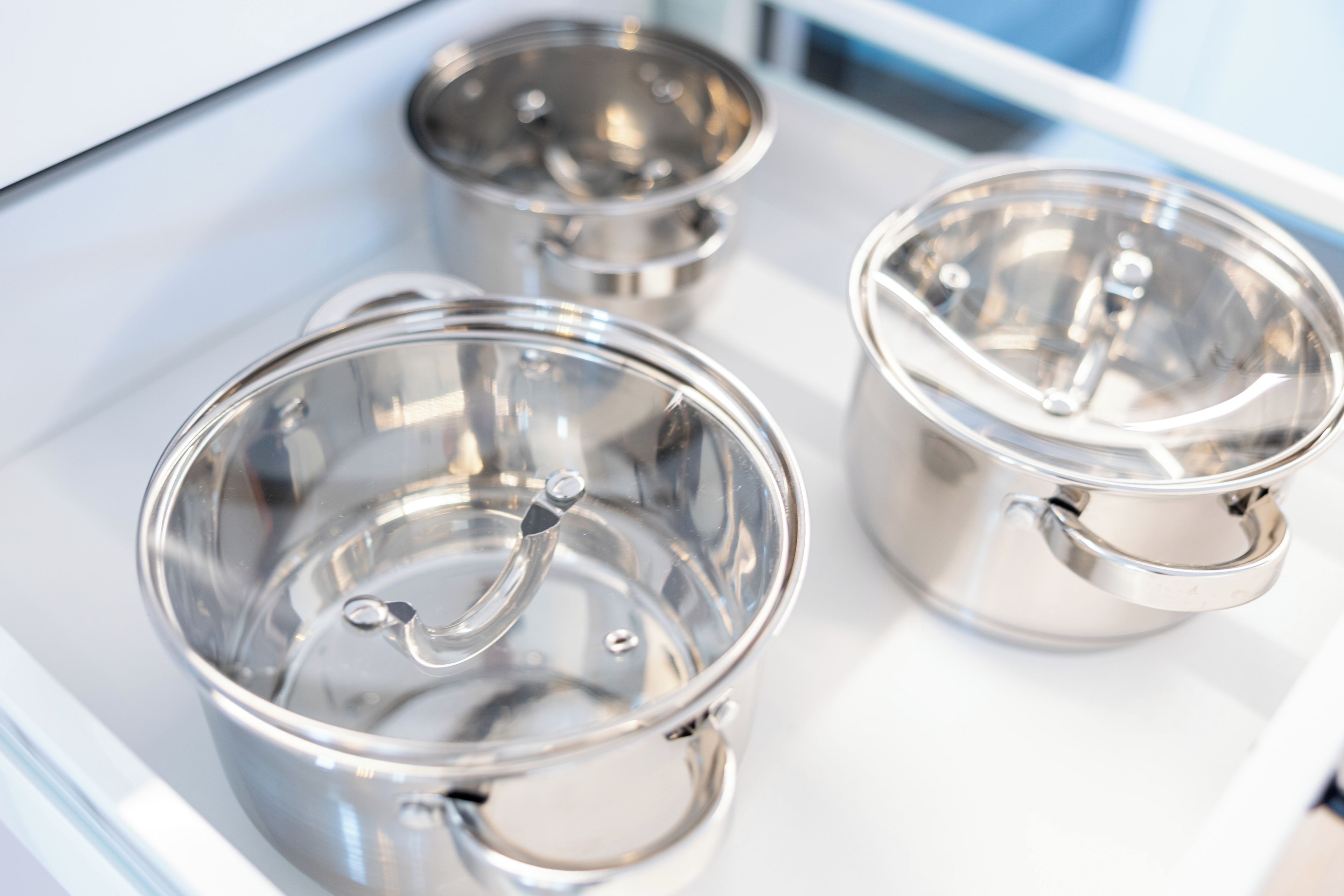 Three stainless steel cups with lids on a white tray.