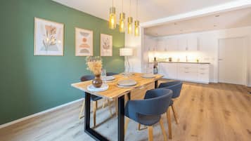 A modern dining area with a wooden table, chairs, and hanging pendant lights.