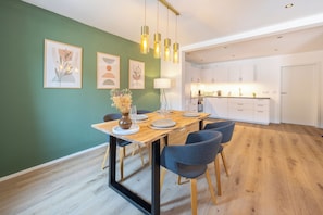 A modern dining area with a wooden table, chairs, and hanging pendant lights. - Simply Stay Homes Bergliebe & Seeglück (Traunstein)