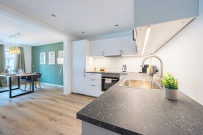A modern kitchen with a granite countertop, stainless steel sink, and a built-in oven. - Simply Stay Homes Bergliebe & Seeglück (Traunstein)