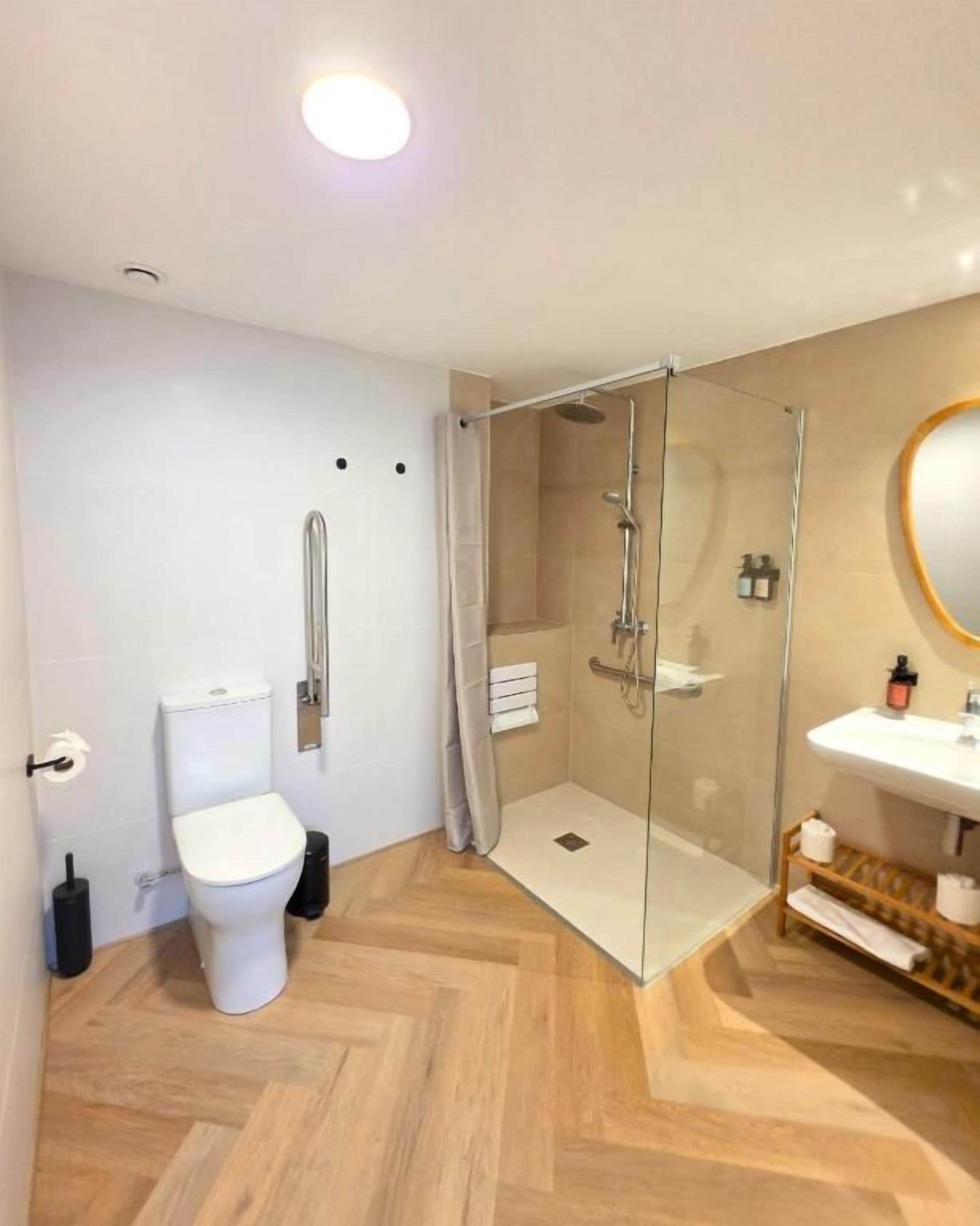 A modern bathroom with a glass-enclosed shower, a white toilet, and a sink with a mirror.