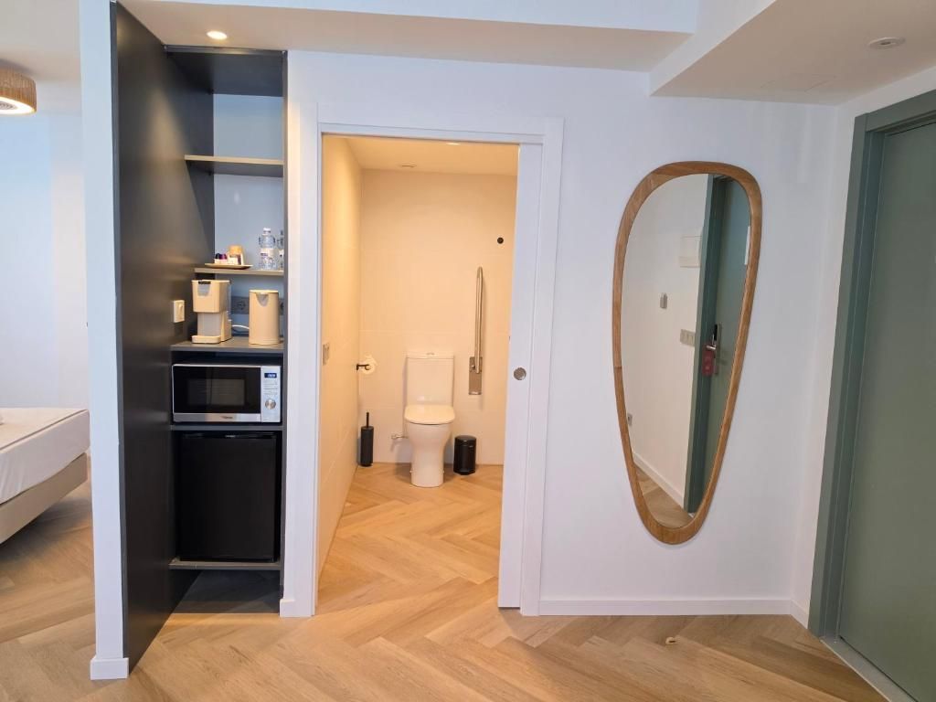 Een moderne badkamer met toilet, hygiëneschuimer en een spiegel.
