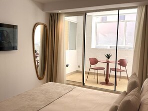A bedroom with a bed, a large mirror, a sliding glass door leading to a balcony with a table and chairs. - Alirena Alicante (ALACANT)