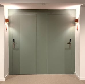 Un par de puertas cerradas, cada una con un interruptor de luz, y un aplique en la pared a la izquierda y otro a la derecha.