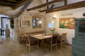 Ein rustikaler Essbereich mit Holztisch, Bänken und einer Steinwand.