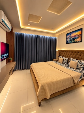 Ein modernes Schlafzimmer mit einem großen Bett, einem Flachbildfernseher und einem Bild an der Wand.
