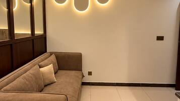 Un salon moderne avec un canapé d’angle, un éclairage encastré et un grand miroir.