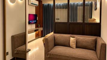 A modern living room with a sofa, a television, and a large mirror.