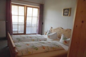 A bedroom with two beds, a window with blinds, a radiator, and a framed picture on the wall. - Holiday apartment with 1 bedroom (Hopfen am See)