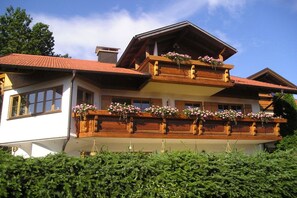A two-story building with a balcony adorned with flower boxes. - Holiday apartment with 1 bedroom (Hopfen am See)