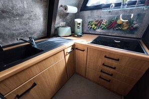 Eine kleine Küche mit einer schwarzen Spüle, einem Toaster und einer Kaffeemaschine.