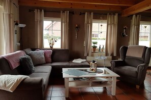 Ein gemütliches Wohnzimmer mit einem braunen Sofa, einem weißen Couchtisch und einem grauen Sessel.