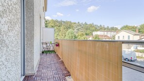 A balcony with a tiled floor, a folding table, and a chair. - Quiet one-bedroom apartment with a large balcony and free parking (Oullins)