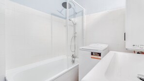A bathroom with a white bathtub, a shower with a handheld showerhead, and a white toilet. - Quiet one-bedroom apartment with a large balcony and free parking (Oullins)