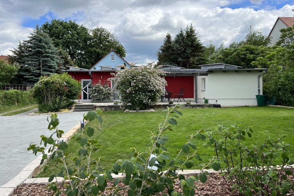 A residential property with a red house, a white garage, and a well-maintained lawn.
