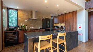Cozinha moderna com ilha central, banquetas de madeira e eletrodomésticos embutidos.