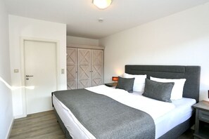 Ein Schlafzimmer mit Bett, Nachttisch, Kleiderschrank und einer Tür.