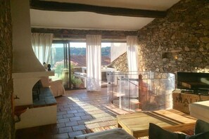 A rustic interior with stone walls, a fireplace, and a balcony overlooking a scenic landscape. - ||----------------------------Holiday home--------------------|| (La Garde Freinet)