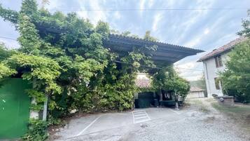 Ein Parkplatz mit überdachtem Eingang, ein Gebäude mit Ziegeldach und ein grüner Zaun.