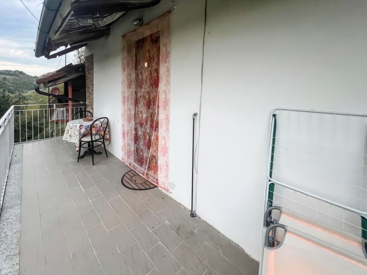 Un balcon avec une table et une chaise, une porte et une rambarde.