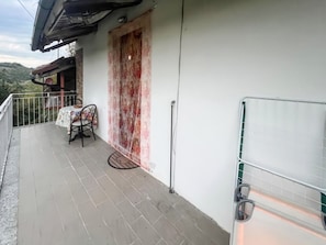 Ein Balkon mit Tisch, Stuhl, einer Tür und Geländer.