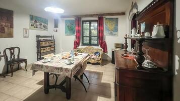 Ein Essbereich mit einem Tisch für vier Personen, einer Couch, einem Bücherregal und einem Kamin.