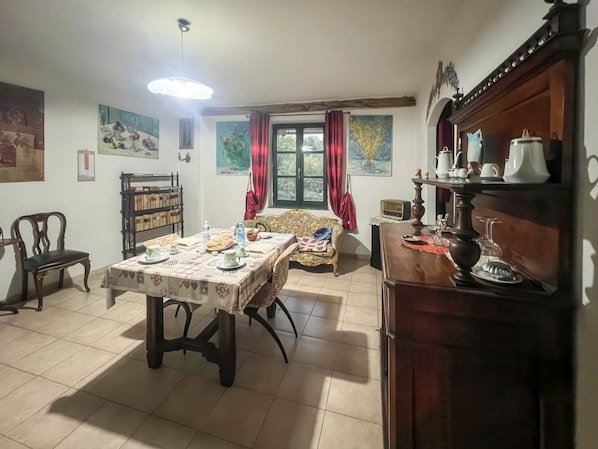 A dining area with a table set for four, a sofa, a bookshelf, and a fireplace.
