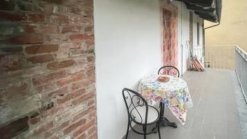 Ein Balkon mit Tisch und Stühlen, eine Ziegelwand und ein Fliesenboden.