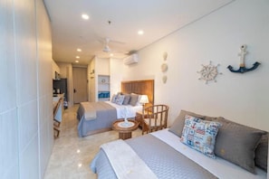 A hotel room with a bed, a sofa, a small table, and a ceiling fan. - El Márquez Bello Horizonte Apartment Suites, Santa Marta (Santa Marta)