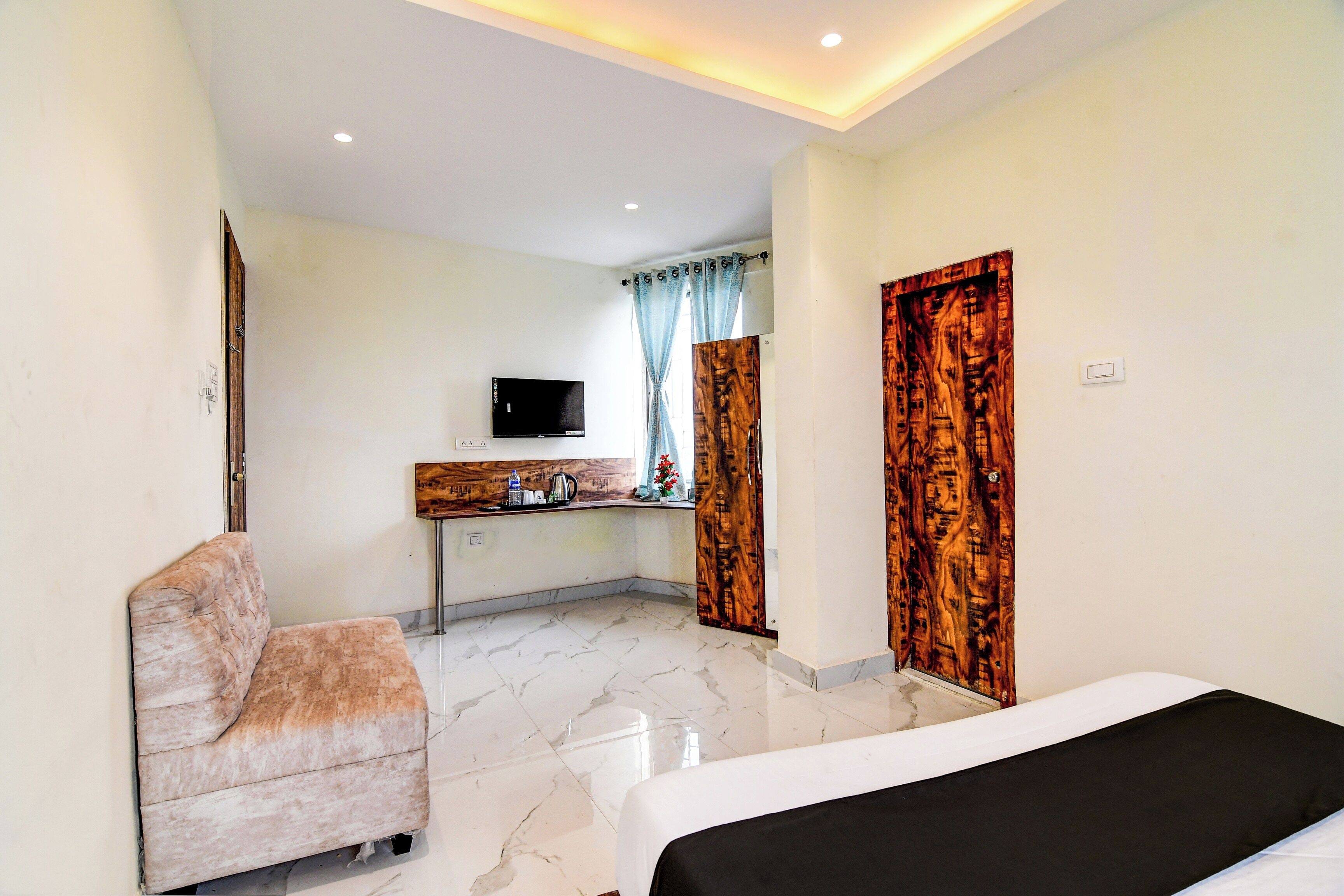 Una habitación de hotel con cama, zona de estar, escritorio y televisión, además de un baño.