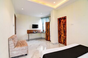 Una habitación de hotel con cama, zona de estar, escritorio y televisión, además de un baño.
