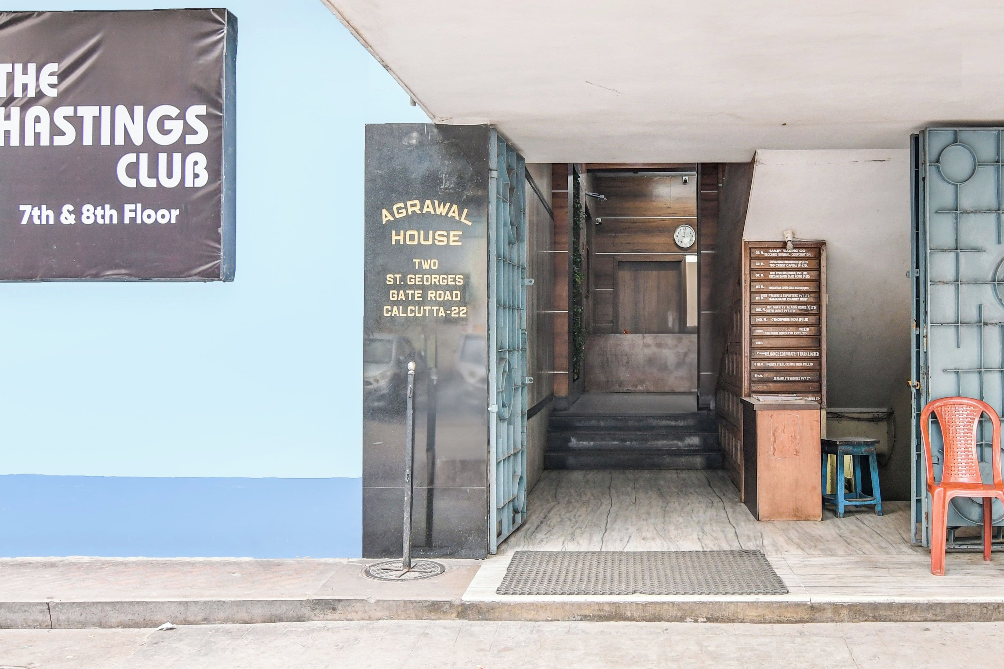 A building entrance with a sign for 'AGRAWAL HOUSE' on the left and a sign for 'THE HASTINGS CLUB' on the right.