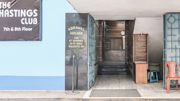 A building entrance with a sign for 'AGRAWAL HOUSE' on the left and a sign for 'THE HASTINGS CLUB' on the right.