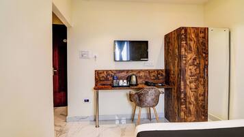 A hotel room with a bed, a desk with a chair, a television, and a wardrobe.