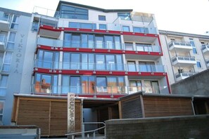 A multi-story building with a red and white facade, balconies, and a sign that reads 'Viktori'. - Strandhuus Norderney (Norderney)