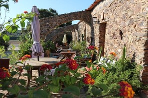 An outdoor seating area with stone arches, tables, and umbrellas. - Holiday apartment with 1 bedroom (Carrapateria)